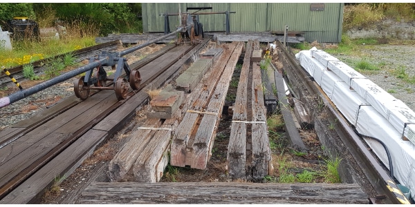 long beams with channels cut next to historic winch on slipway with shed behind