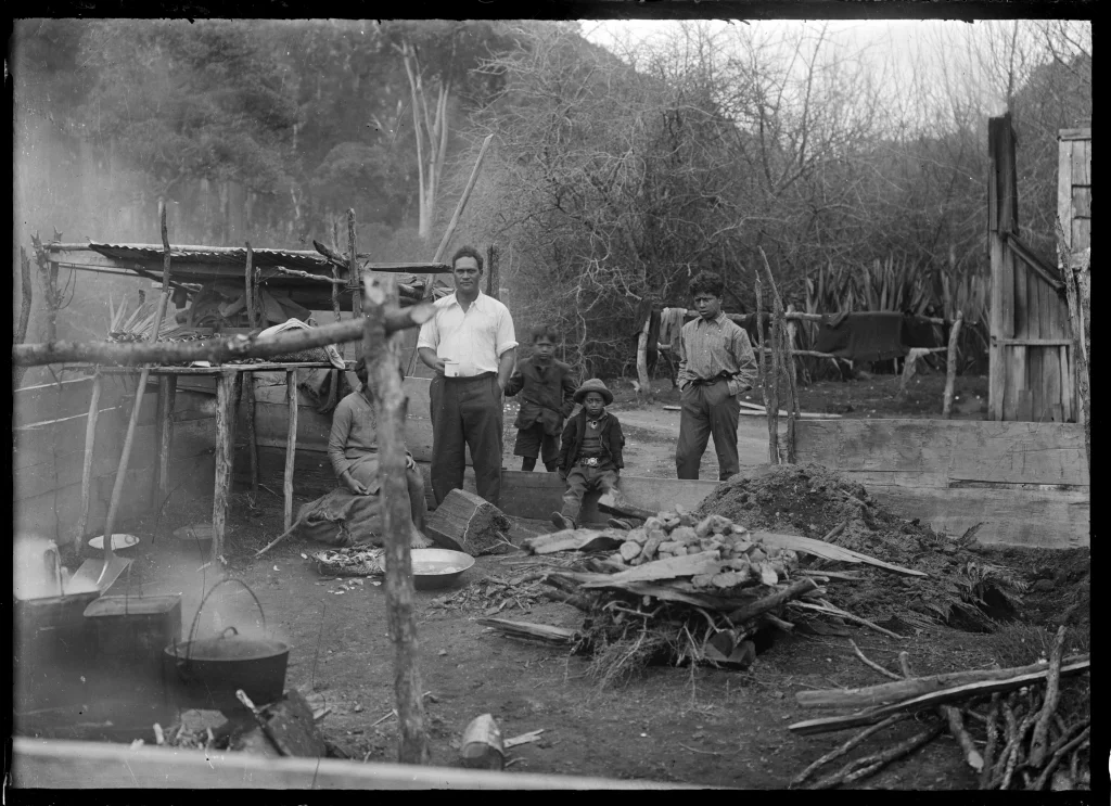 A group of men around a hangi at Te Whaiti. Photograph taken by Albert Percy Godber in October 1930.