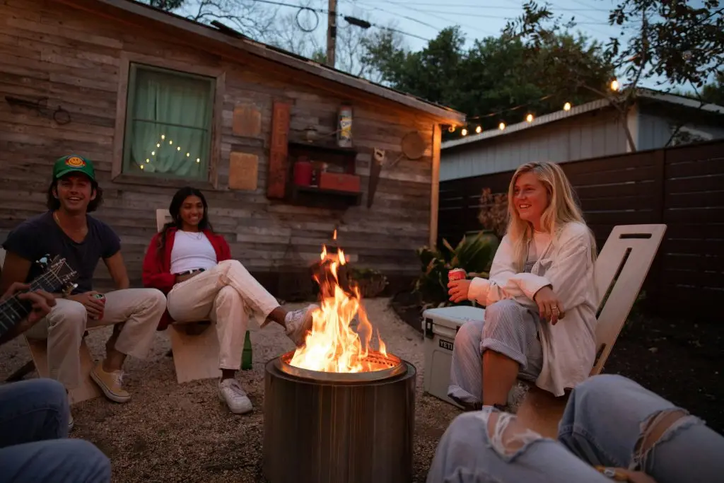 Young friends relaxing in the backyard around a firepit at night, on Trippy Chairs